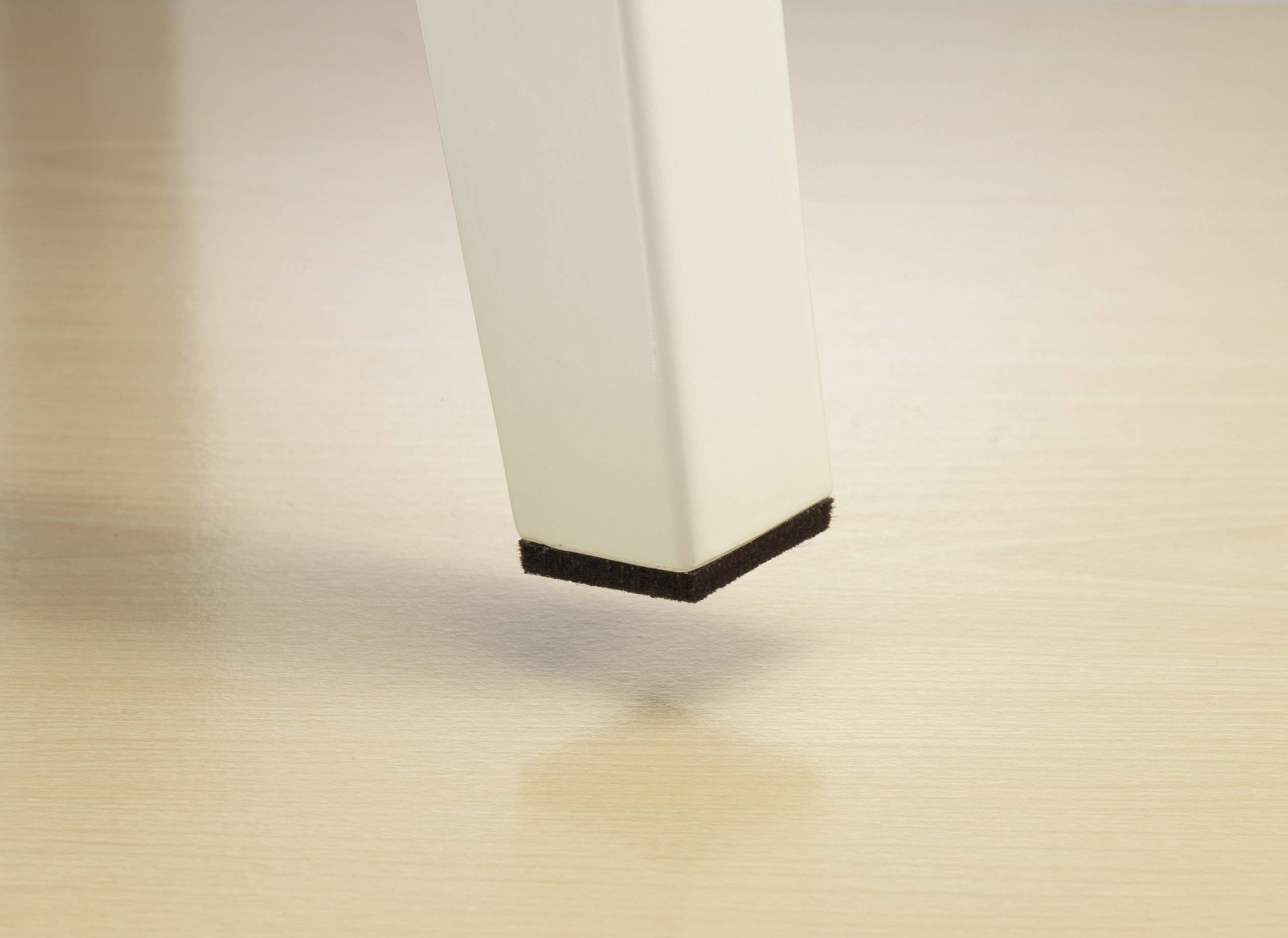 A white table leg with a black felt glide surface hovers just above a light wooden floor.