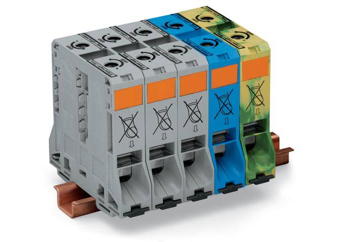 Four circuit breakers mounted side by side in different colours on a DIN rail, symbolising electrical protection switches.