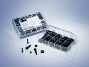 An open plastic container with multiple compartments, filled with black screws and nuts. Some parts are lying beside it.