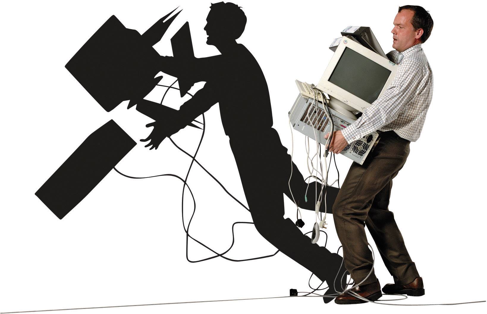 A man is carrying several bulky old computers and cables. His shadow suggests that the devices might fall.