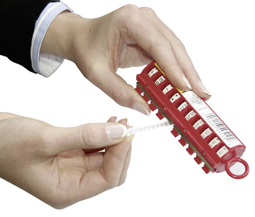 'A person is pulling a label from a red label printer. The device has several numbered compartments and a viewing window.'