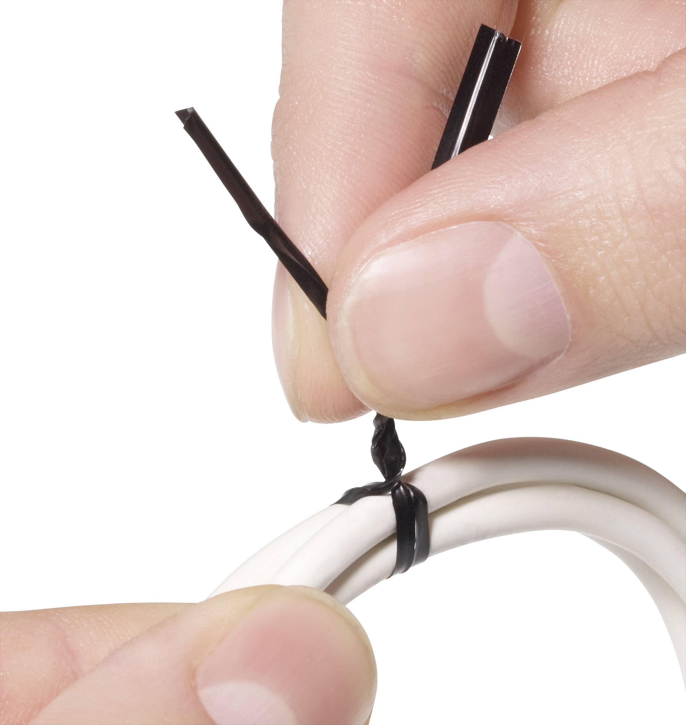 A hand fastens a black cable tie around a white cable to secure or organise it.