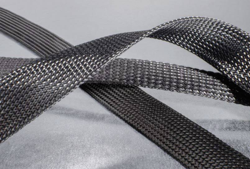 Two crossed straps made of black, braided material on a grey background, indicating durability and strength.