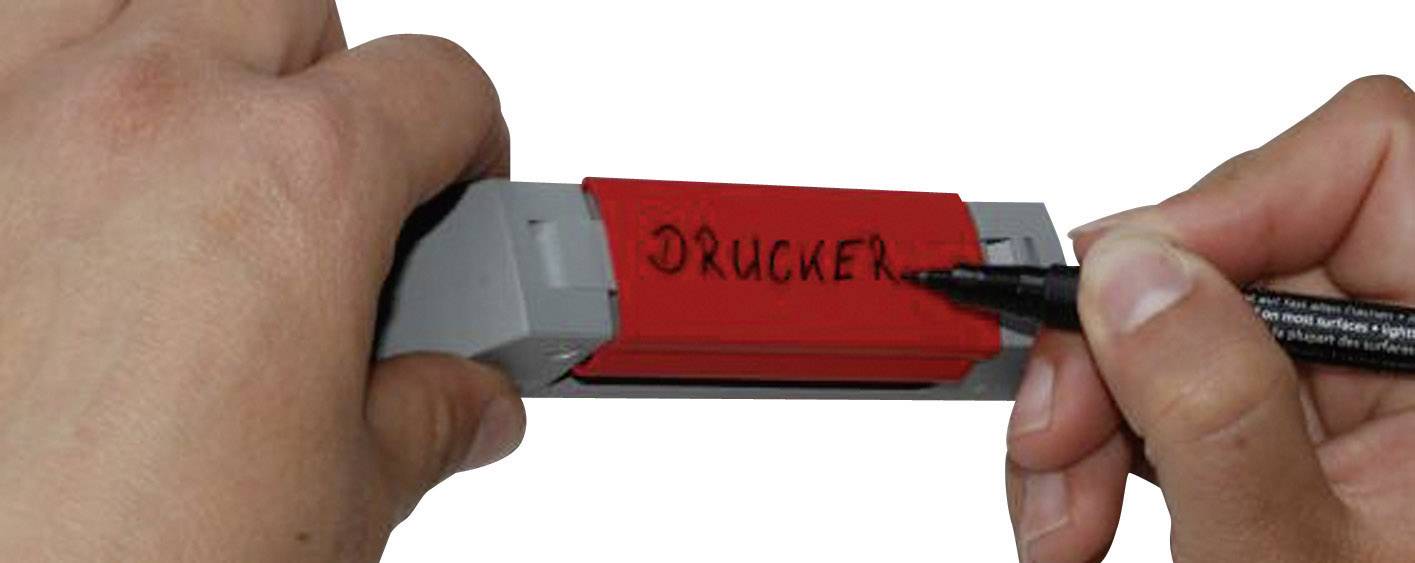 A person is labelling a red label holder with 'Printer' using a black pen.