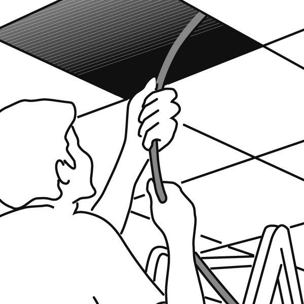 A person is pulling a cable through an opened ceiling panel in an office. A ladder is visible in the foreground.