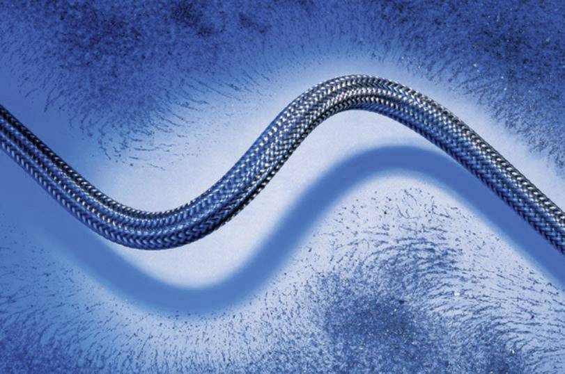 A wavy stainless steel hose lies on a blue, speckled surface, with light emphasising shadows and texture.