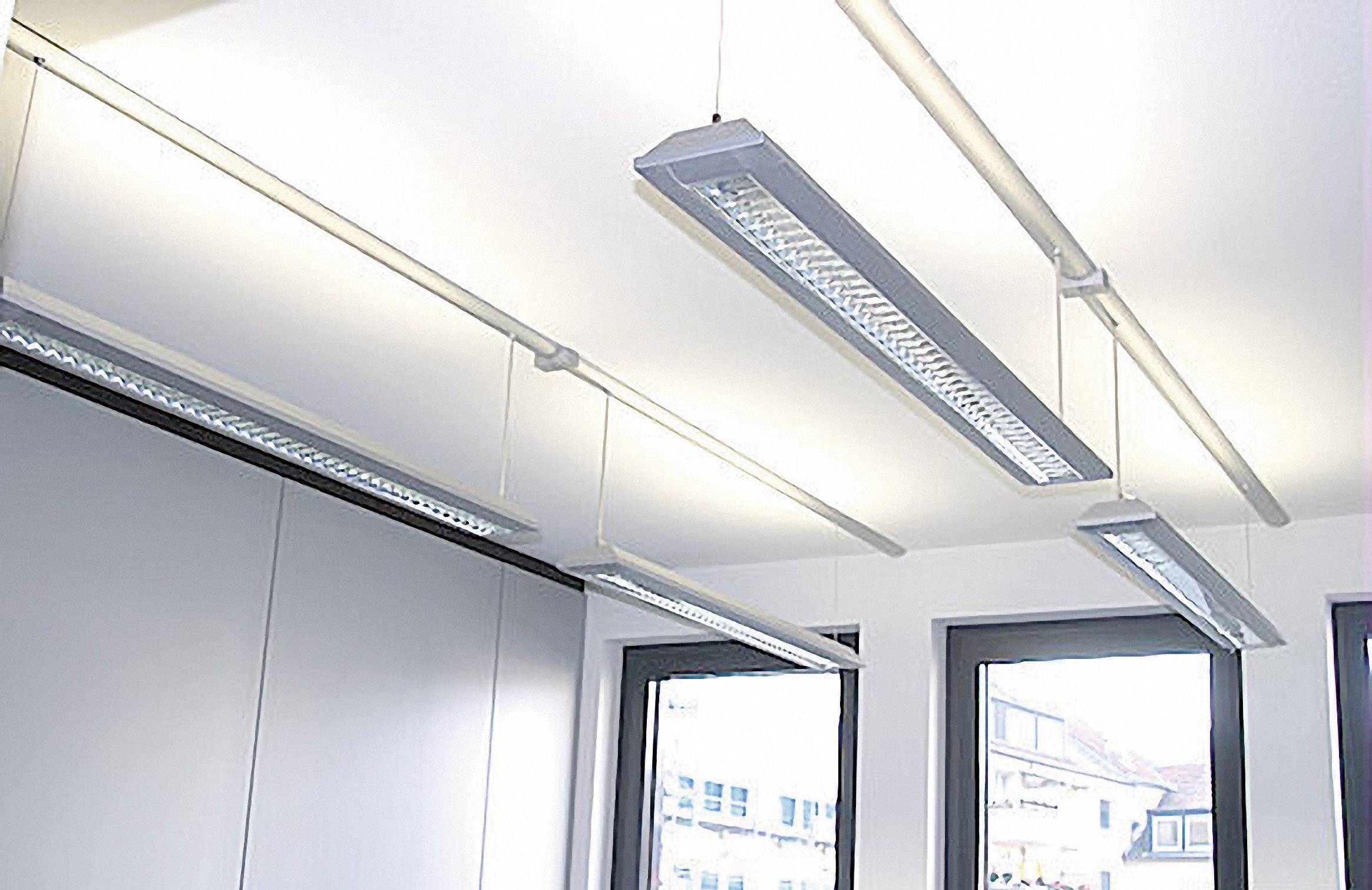 Illuminated office with modern, white pendant lights hanging from the ceiling and large windows allowing plenty of natural daylight to flood in.