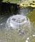 A circular fountain with dome-like spray in a pond, surrounded by lily pads. Water droplets splash in a crisp pattern.