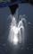 A illuminated fountain sprays water in a dark pond, the light creating a luminous effect on the water jets.