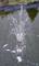 Small fountain in a pond sprays water jets into the air, with a green background and a slight reflection in the water.