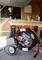 A craftsman wearing ear protection is sawing wood at a workbench in a workshop. A cable drum is located in the foreground.