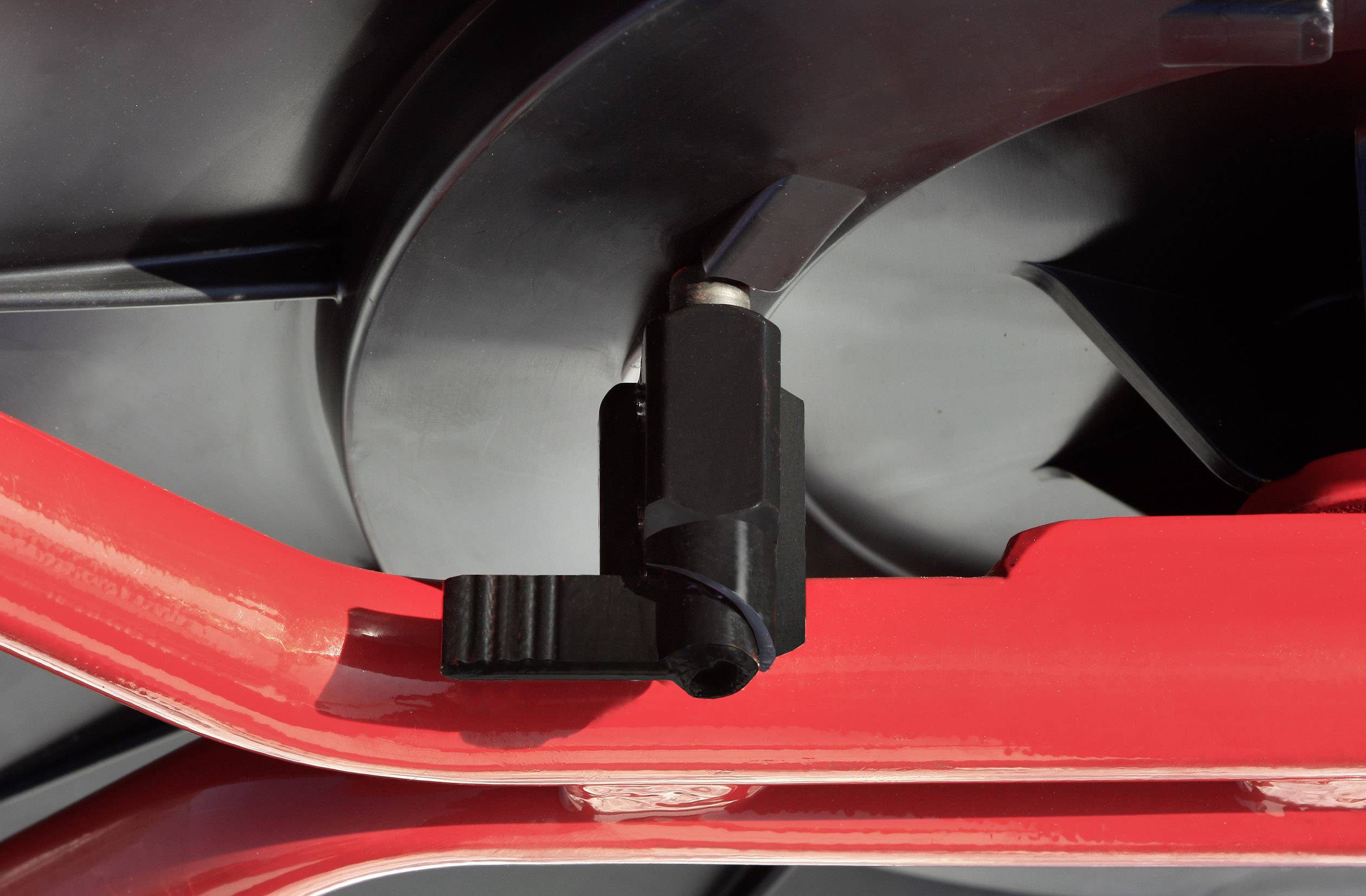 Close-up of part of a machine with a black and red component. The black component is attached to the red structure.