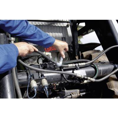 A person is repairing or maintaining the hydraulic hoses of a tractor. Their hands are holding tools and hoses at a metal fixture.