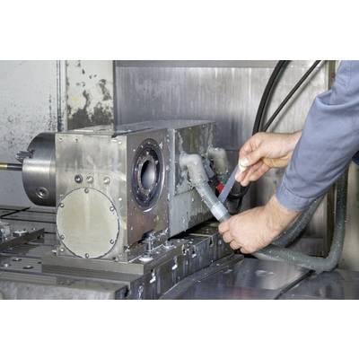 A person in workwear is installing or inspecting hoses on an industrial machine in a workshop environment.