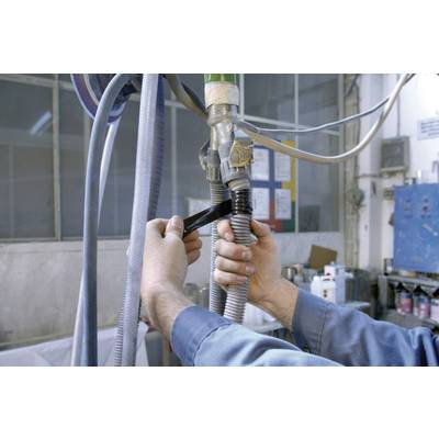 A person is repairing a hose in a workshop with black gaffer tape to secure a connection. Tools are visible in the background.