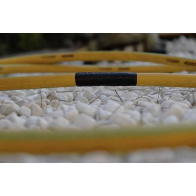 A yellow garden hose lies on white pebbles. The hose has a black section. Background slightly blurred.