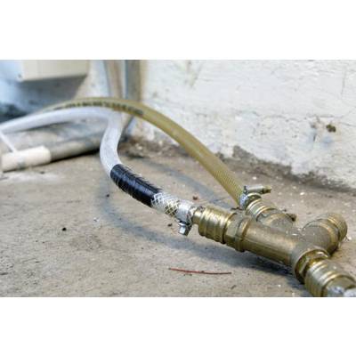 A utility water hose with two valves connects pipework on a wall above a concrete floor.
