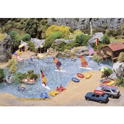 A model of a lake with many sailing boats and bathers, surrounded by trees and a small building on the right.