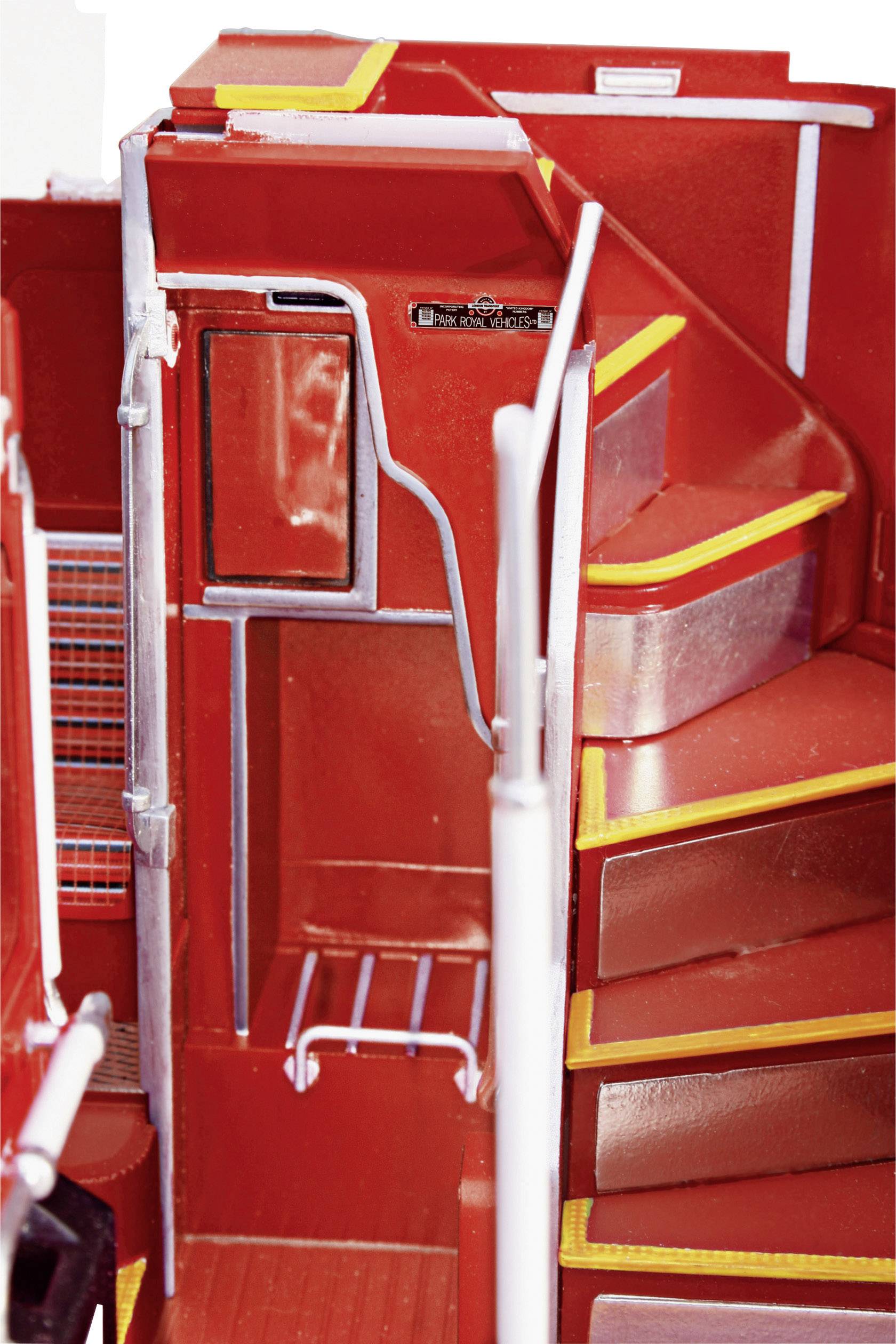 'The interior of a red bus, showing steps leading up to an upper level, surrounded by metal handrails.'
