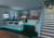 Modern kitchen with an island, bar stools and subtle lighting. A staircase leads upstairs. Shelving with books and decorative items.