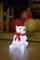 A luminous polar bear with a red bow sits on the ground. Blurred, colourful balloons are visible in the background.