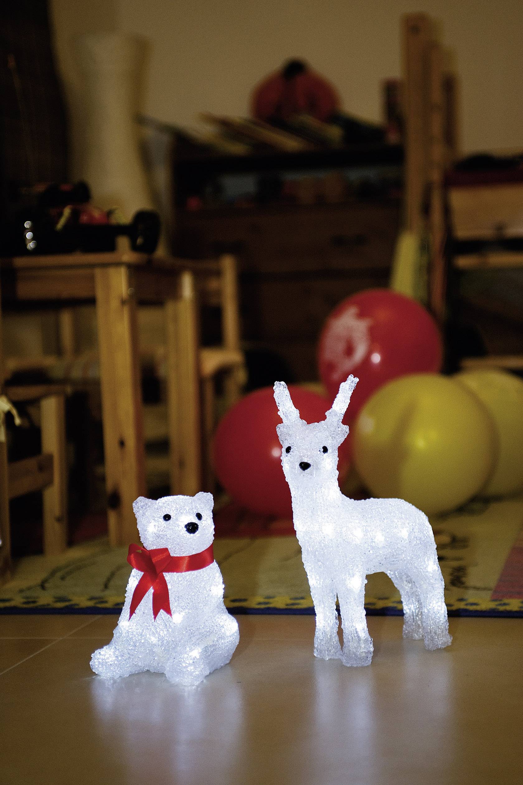 A luminous polar bear and a reindeer wearing a red scarf stand on a carpet in a festively decorated room with balloons in the background.