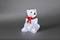 A decorative polar bear made of transparent material with illuminating elements, wearing a red bow around its neck against a grey background.