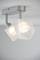 Ceiling light with two hexagonal, white lamp shades that emit bright light. They are suspended from silver brackets.