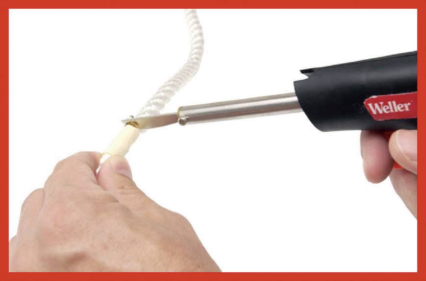'A hand is holding a soldering iron, which is pointed at a rope in order to seal its end, presumably to prevent fraying.'