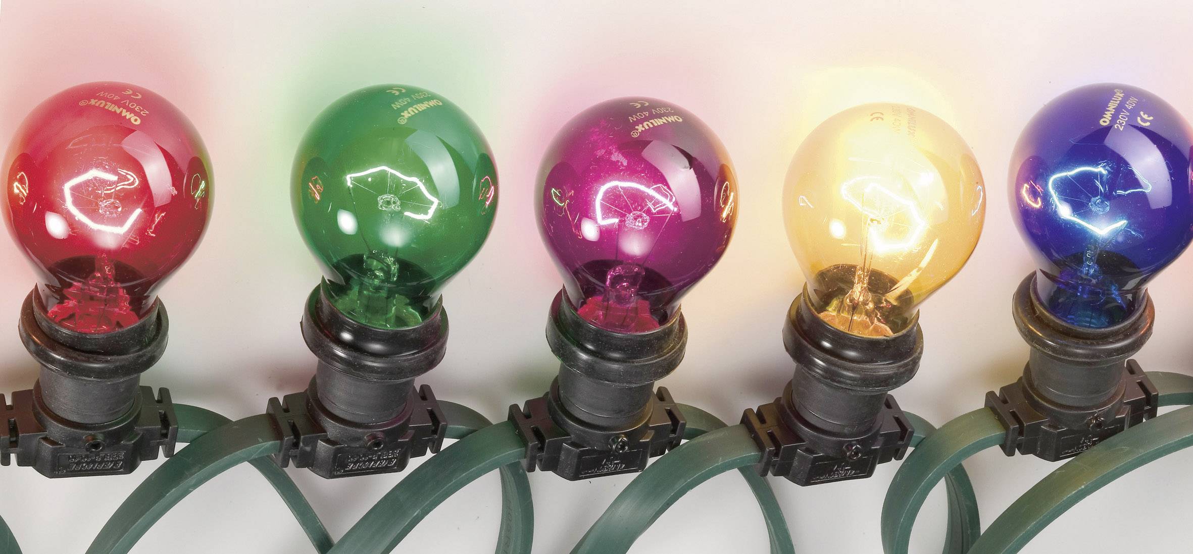 Five colourful light bulbs shine in red, green, pink, yellow and orange on a row of cables.