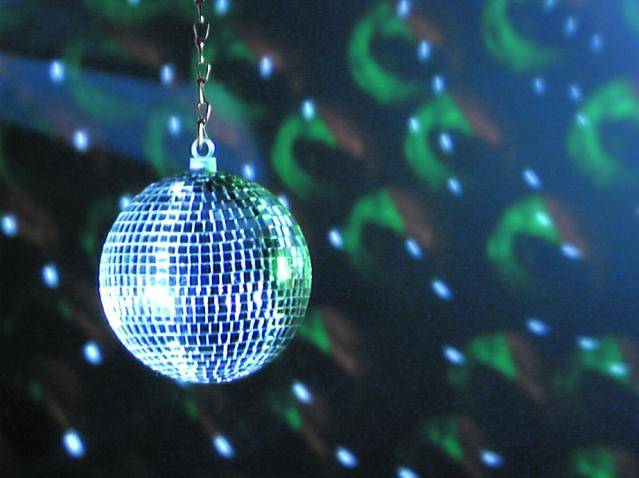 A disco ball reflects colourful lights in a dark room. Light effects create a vibrant, festive atmosphere.