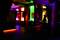 A dimly lit room in a bar or club with colourful lights on the walls, a bar and bar stools in the foreground.