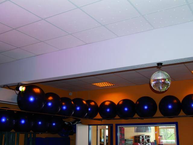 A colourful illuminated room with gym balls hanging from the ceiling and a glitter ball in the centre; sporty atmosphere.