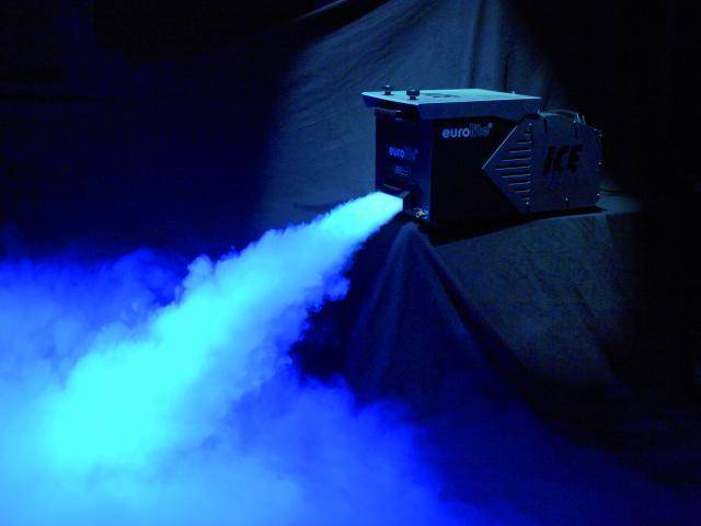 Fog machine emits dense blue smoke to create a mystical atmosphere. Background dark, stage not visible.