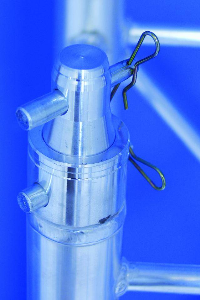 Metal connection with three cylindrical pins and fixing clamps against a blue background.