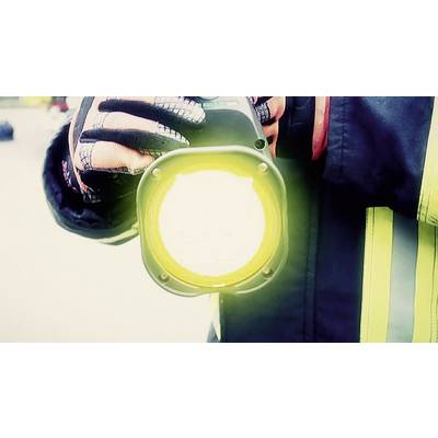 A firefighter is holding a bright torch. The reflective strips on his jacket are visible.