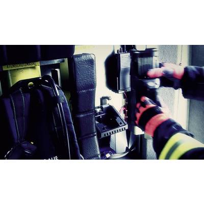 A firefighter in protective clothing is adjusting equipment in an emergency vehicle. Protective gloves and equipment are visible.
