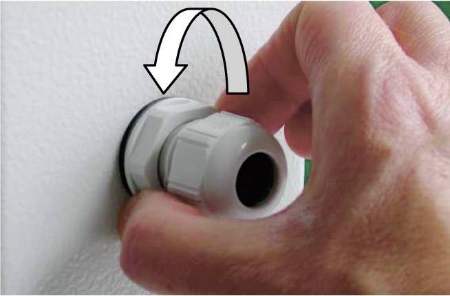A hand is turning a cable gland to secure it to a device base. An arrow indicates the direction of rotation.