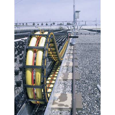 A cable drag chain on rails in an industrial setting, with empty planting containers on the left. The scene appears technical and orderly.