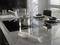 A modern kitchen with an induction hob, on which a large saucepan sits. A hand blender rests on the grey worktop.