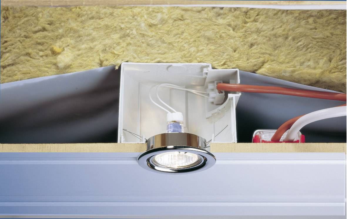 Recessed light fitting with open housing in the ceiling area, cables and insulation material visible.
