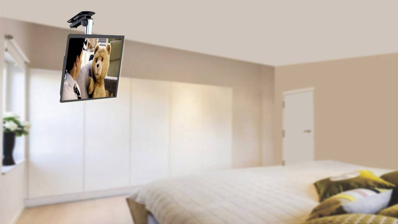 A bedroom with a bed in the foreground. A television is mounted on the ceiling, showing a film featuring a bear.