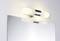 Wall light with two cylindrical, white luminaires above a rectangular mirror.