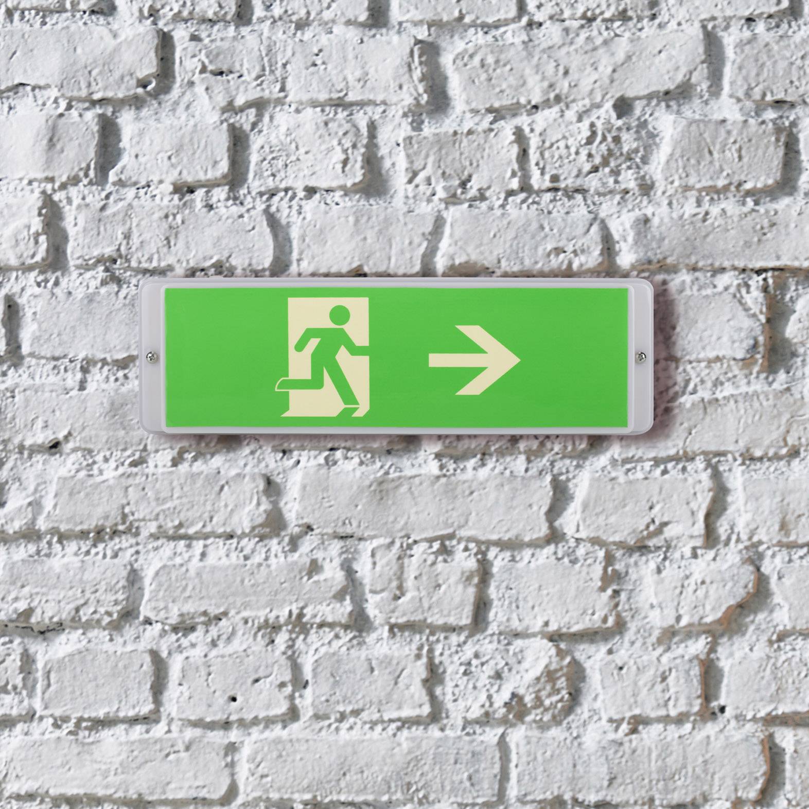 Green emergency exit sign on a brick wall, showing a figure pointing towards an arrow to the right.