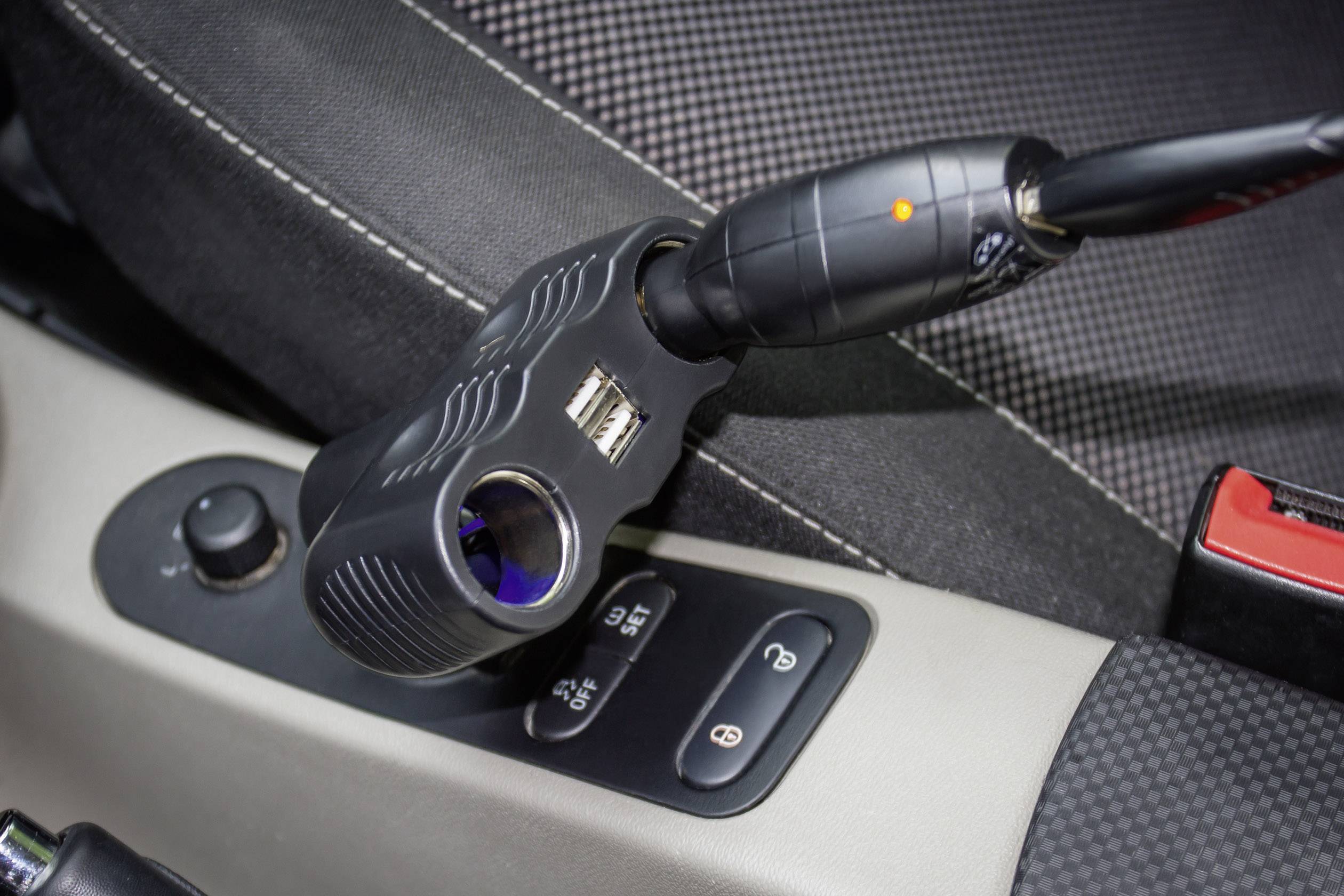 A car adapter plugs into a socket in the car. It has USB ports to charge devices while driving.