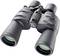 A black pair of binoculars with green-tinted lenses sits on a white surface. It is ready for observation.