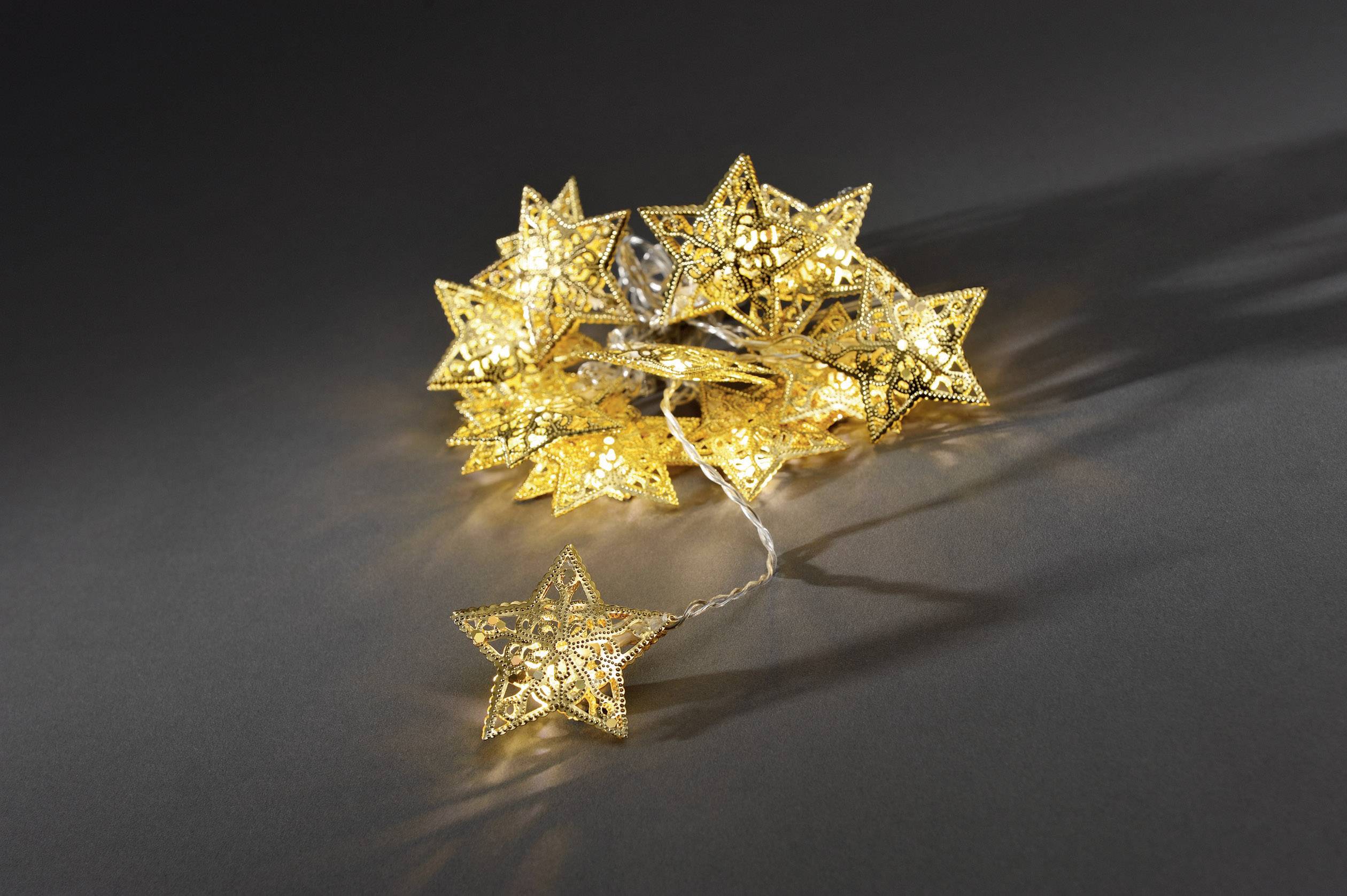 Golden Star String Lights Illuminate on a Grey Background, Each Lamp Shaped like a Detailed Star with Intricate Patterns.