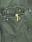 Green jacket pocket with two buttons and an open zip, with a yellow cord stopper protruding from it.