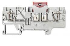 Grey-white electrical terminal block with metal parts and a red lever on top, used for connecting multiple cables in a control panel.