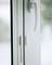 A white window handle on a closed glass window. The image depicts a functional detail for operating the window.